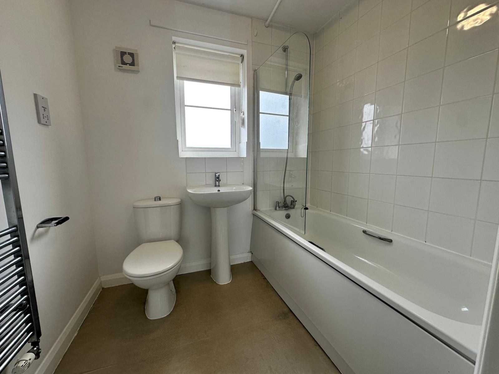 Bathroom with bath, shower over, glass screen and heated towel rail