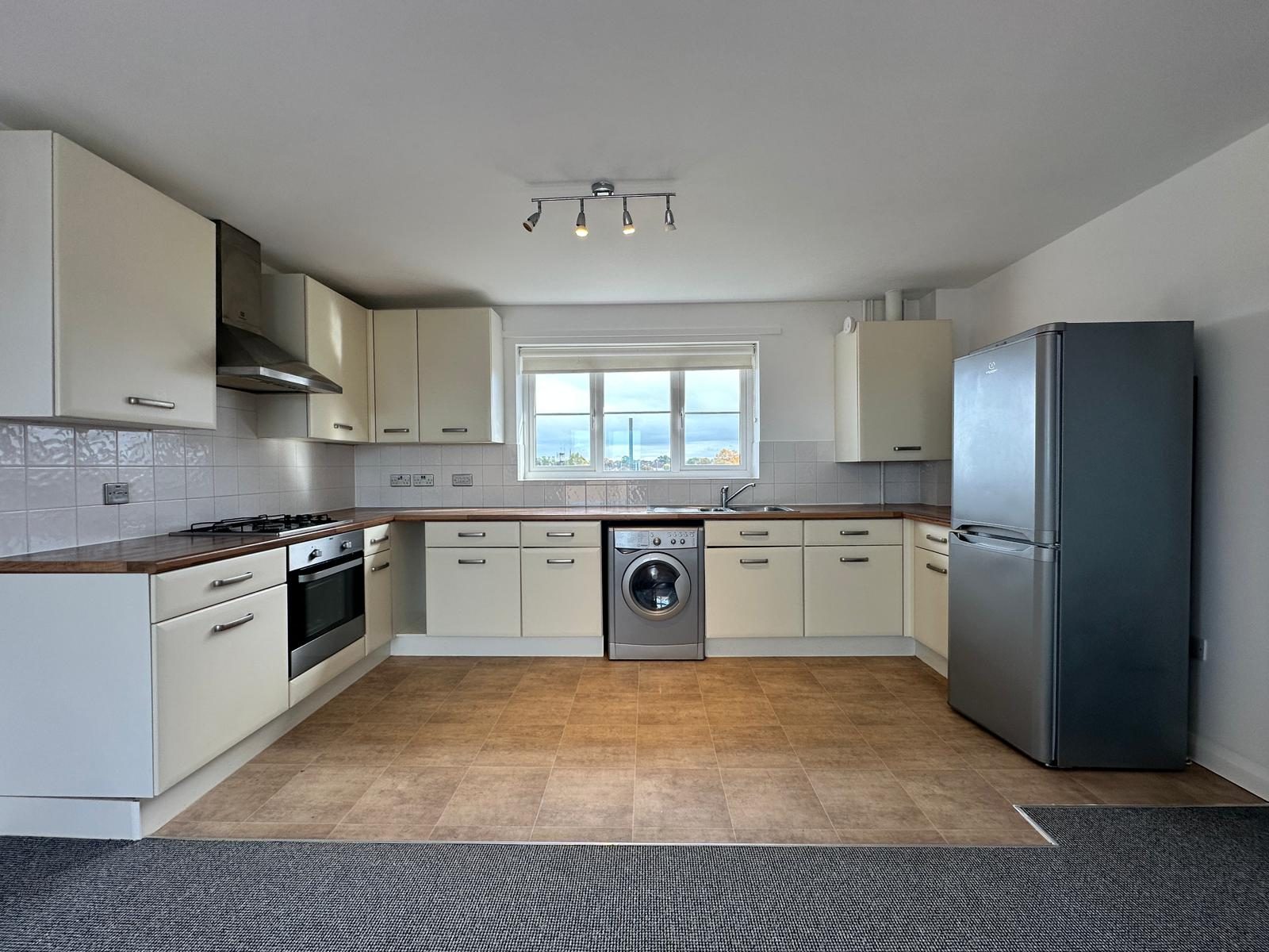 Fitted kitchen with gas hob, oven, extractor hood, washing machine and fridge freezer